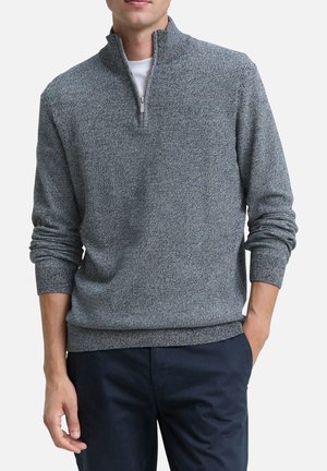 Sweater gris zippé avec un motif de tricot texturé, doté d'un col montant et de poignets côtelés. Associé à un pantalon bleu marine.