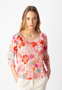Top leggero con motivo floreale in rosa, con fiori arancioni, rossi e blu teal. Maniche a tre quarti e scollatura ampia.
