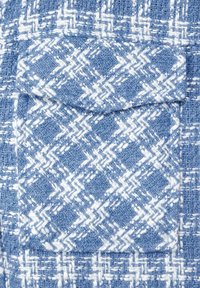 Blå och vit vävd tyg med ett zigzag-mönster, med en fyrkantig fickklaff på framsidan som har en texturerad yta.