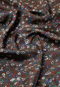 Barna virágos szövet, amely apró, piros, kék és fehér színű, zöld levelekkel díszített virágokat ábrázol, sima textúrával és folyékony eséssel.