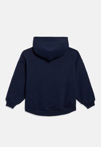 Tamsiai mėlynas džemperis su gaubtu, minkšta tekstūra, didelis gobtuvas, laisvas siluetas ir ribuotos rankogaliai. Apačios kraštas šiek tiek išlenktas.