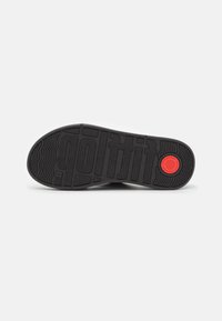La soletta della scarpa presenta un design in gomma nera testurizzata con un accentuato cerchio rosso e un motivo in rilievo "gottit".