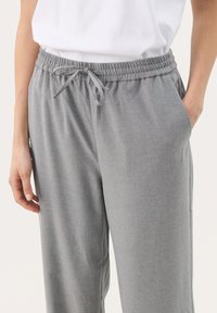 Gray sweatpants with an elastic waistband, drawstring closure, side pockets, and a soft, textured fabric. Casual fit with a straight leg.