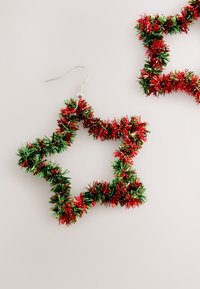 Red and green star-shaped earrings made of tinsel with a silver metal hook. Features a fluffy texture and vibrant color contrast.