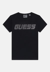 Juodas trumpomis rankovėmis medvilninis marškinėlis su dideliu blizgučių "GUESS" logotipu per krūtinę. Klasikinio apvalaus kaklo dizainas.