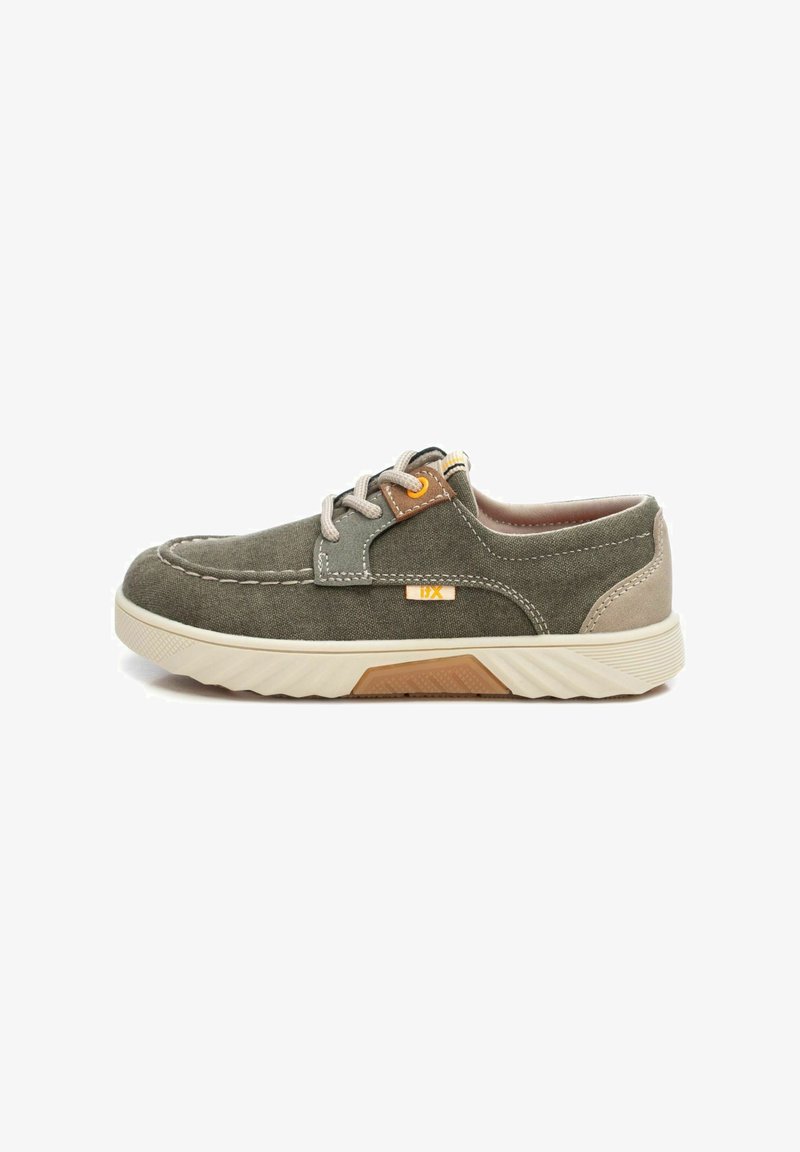 Zapatillas de lona verde oliva con acentos beige, puntera redonda, mediastuela de goma blanca y suela de agarre texturizado; incluye cordones grises y detalles naranjas.