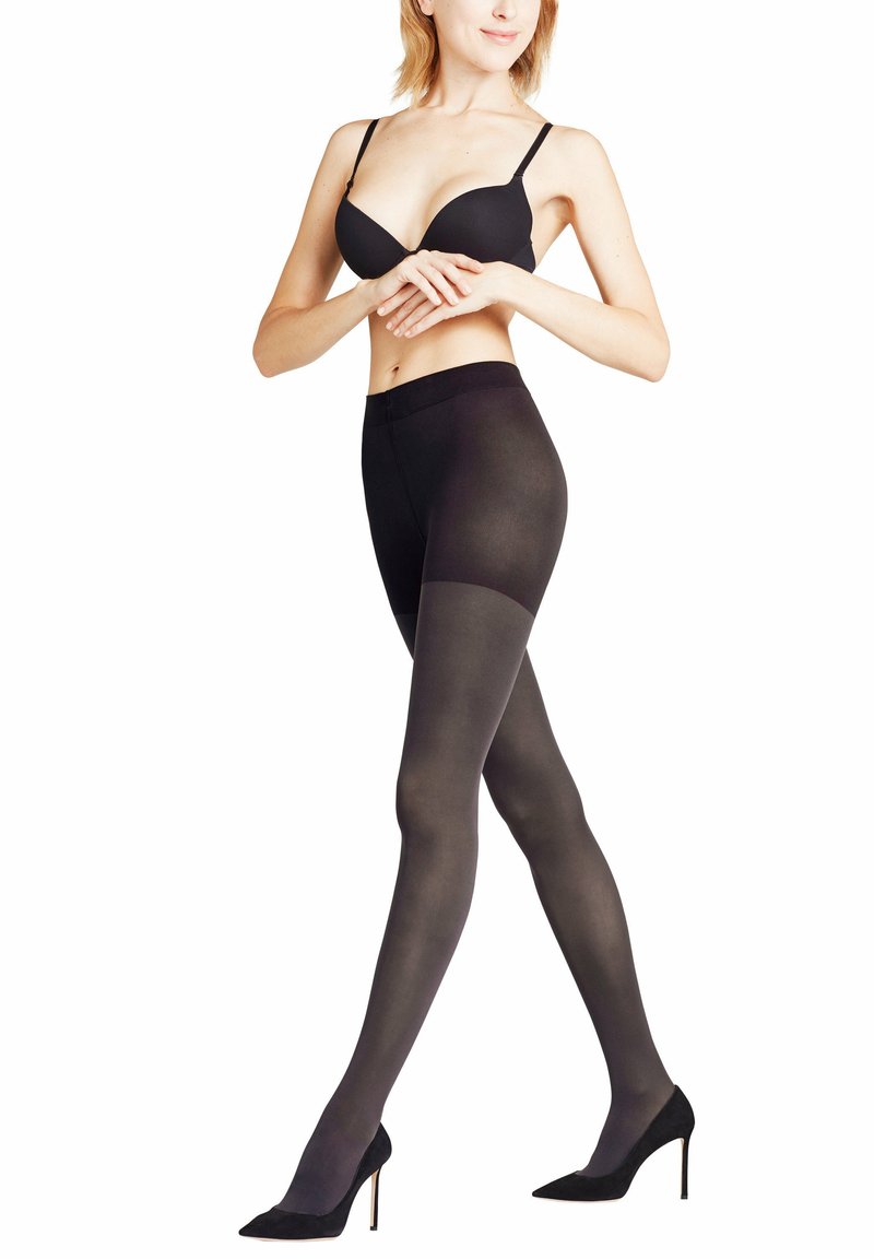 Sorte uigennemsigtige strømpebukser med en glat tekstur, der har en høj talje og en overgang til en gennemsigtig top. Sammen med sorte højhælede sko.