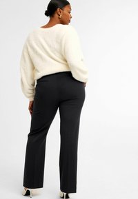 Vitt fluffigt tröja med ballongärmar, tillsammans med svarta åtsittande byxor. Outfiten kompletteras av svartvita högklackade skor.