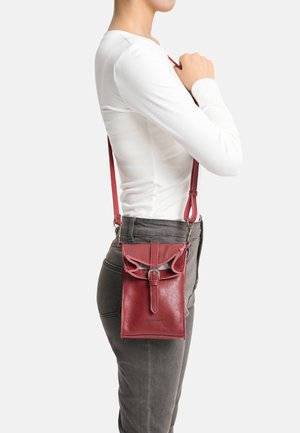Red leather crossbody bag with a textured finish, adjustable strap, and a flap closure featuring a buckle detail.