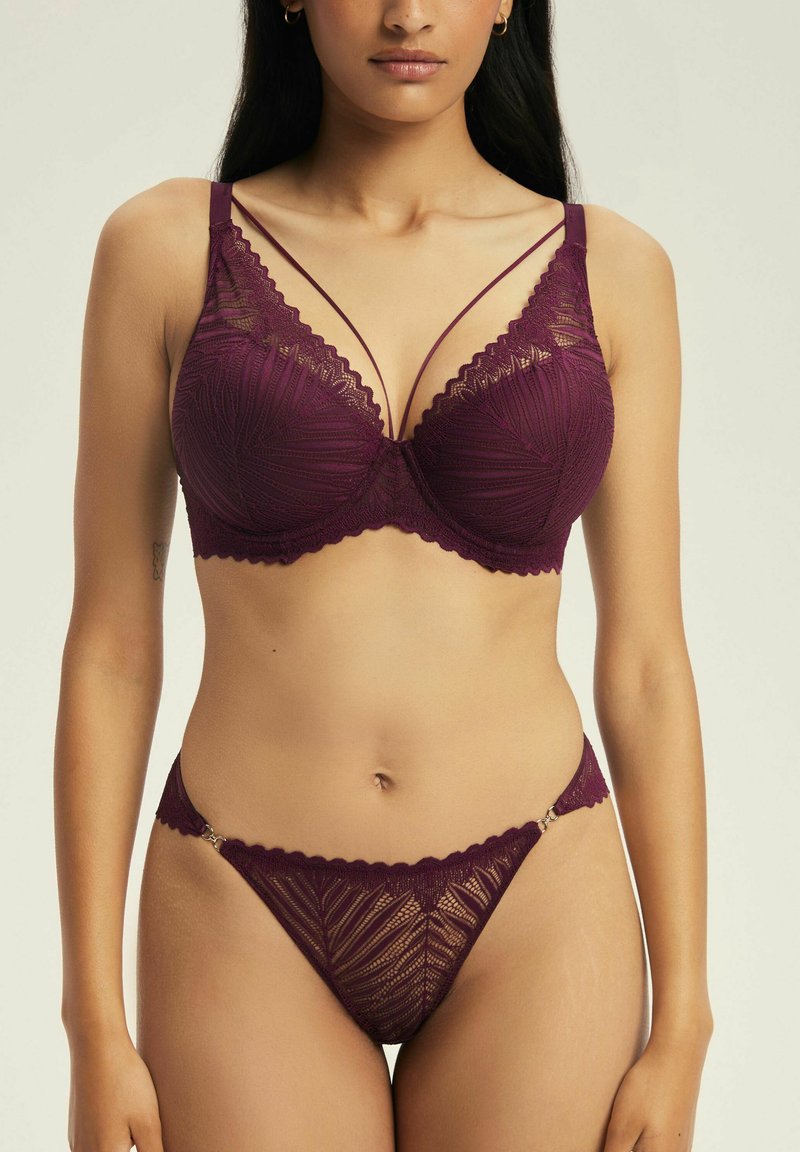 Bordowy zestaw bielizny koronkowej, w skład którego wchodzi biustonosz z ozdobnymi paskami i falbaniastymi brzegami, w zestawie z pasującym stringami z bocznymi akcentami.