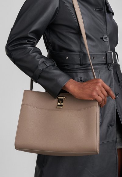 Beige Lederhandtasche mit einer strukturierten Form, ausgestattet mit einem goldfarbenen Verschluss und einem langen Tragegurt. Die Oberfläche hat eine strukturierte Verarbeitung.