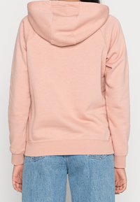 Ljusrosa hoodie med känguruficka, ribbade muddar och nederkant. Tillverkad av mjukt material med en avslappnad passform.