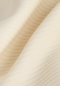 Rippstoff in Cremefarbe mit weicher Textur und dezenten Linien. Das Material wirkt leicht und glatt und erzeugt sanfte Falten.