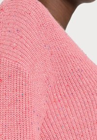 Pull en maille rose à manches courtes avec un motif texturé et des éclats multicolores, doté d'un col rond et de finitions côtelées.
