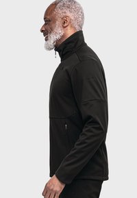 Black zip-up jacket made from soft, textured fabric. Features a high collar, side zip pockets, and a fitted silhouette.