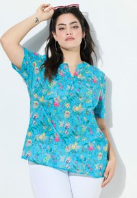 Blusa floreale blu con maniche corte, caratterizzata da un collo henley con bottoni. Il tessuto ha una consistenza leggera con motivi di fiori multicolore.