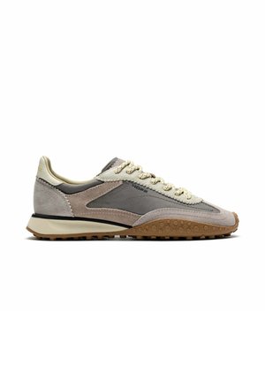 Vista lateral de una zapatilla baja gris y beige con detalles de ante, cordones crema y suela de goma marrón texturizada.