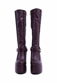 Stivaletti in pelle sintetica marrone al ginocchio con finitura lucida, dotati di cerniere laterali e dettagli con cinturino e fibbia.