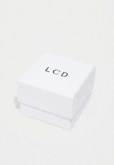 Biely štvorcový box s nápisom "LCD" vytlačeným čiernou farbou na vrchu, zatvorený a ležiaci na svetlom povrchu.