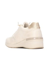 Zapatilla beige con un upper texturizado, acento metálico dorado en el talón y suela de cuña. Los cordones están asegurados con un toggle para facilitar el ajuste.