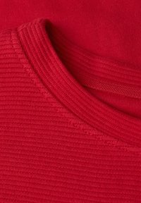 Tessuto rosso a coste con scollatura rotonda; la texture appare morbida e liscia, mostrando un colore uniforme senza motivi o dettagli aggiuntivi.