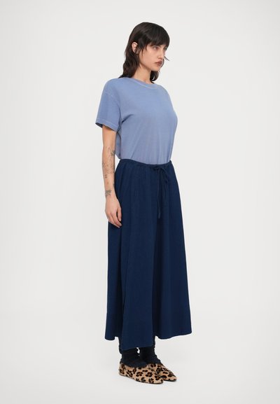 Σιέλ κοντομάνικο T-shirt συνδυασμένο με φούστα σε σκούρο μπλε χρώμα με φαρδιά μπατζάκια και ζώνη με κορδόνι στη μέση, φορεμένα με παπούτσια με λεοπάρ μοτίβο.