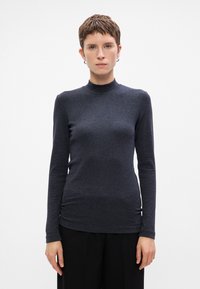 Tamsiai pilkas ilgomis rankovėmis turtleneck stilius viršus, pagamintas iš lygios, tamprios medžiagos. Pasižymi prigludusia siluetu ir minimalistiniu dizainu be raštų.