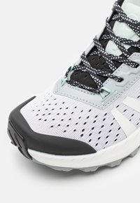 Chaussure de course légère avec une tige en mesh blanc respirant et des accents noirs, un capuchon en caoutchouc pour les orteils et une semelle rembourrée pour une meilleure traction.