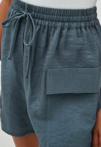 Blaue, leichte Shorts aus strukturiertem Stoff. Sie verfügen über einen elastischen Bund mit Kordelzug und einer großen Seitentasche.