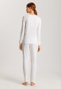 Top de manga larga blanca y pantalones a juego, hechos de una tela suave. Diseño simple con un escote redondo y forma ajustada, que enfatiza la comodidad.