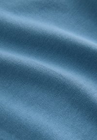 Țesătură albastru deschis cu o textură netedă și o împletitură strânsă, evidențiind variații subtile de nuanță și un finisaj moale, mat.