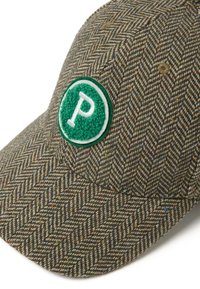Gorra de patrón espiga en tweed gris y marrón. Presenta un parche circular de fieltro verde con un logo blanco de "P". Textura suave, visera curvada.