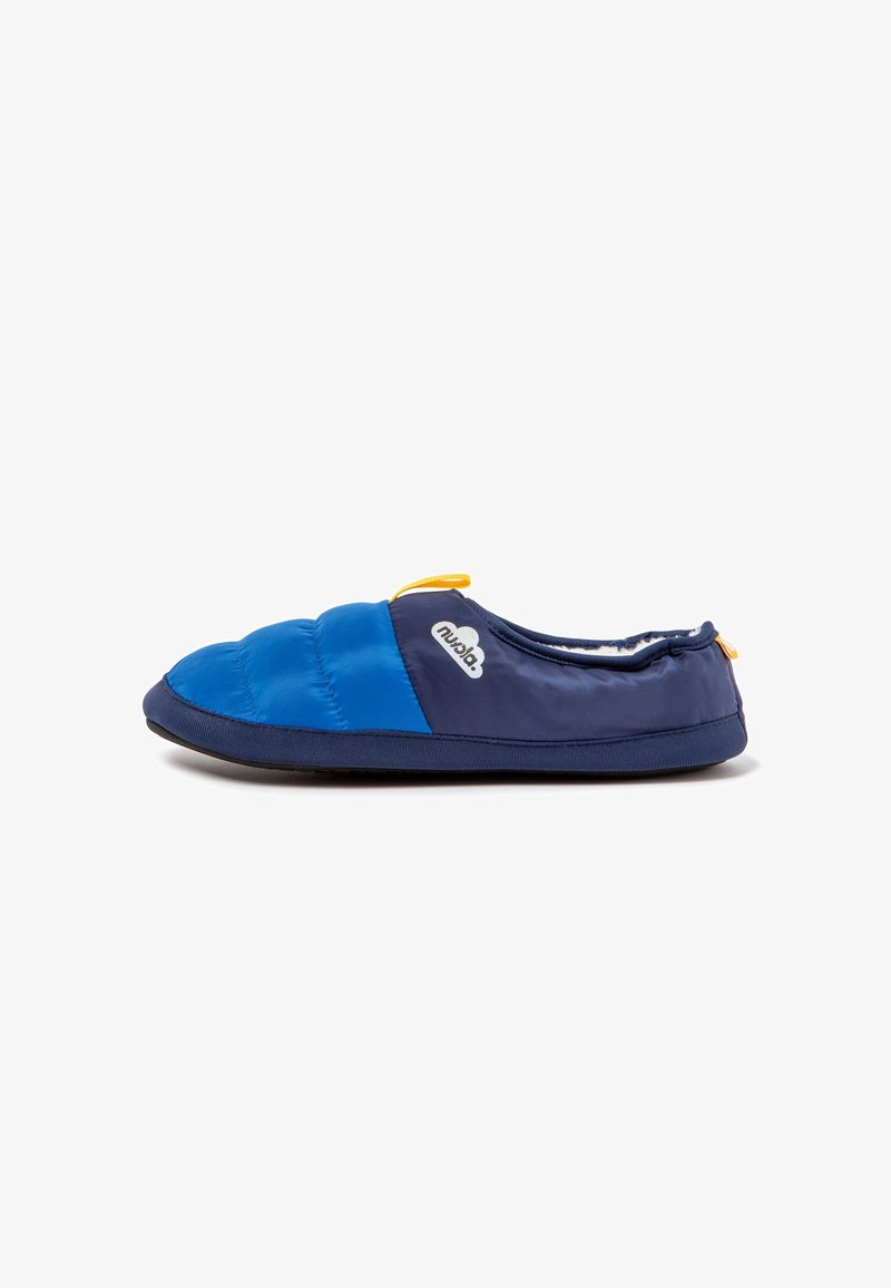 Zapatilla acolchada en azul marino y azul con un exterior suave, suela de goma y un lazo amarillo para facilitar su uso. Cuenta con una plantilla acolchada.