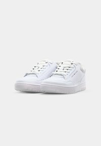 Paire de baskets basses blanches Tommy Hilfiger avec lacets et logos de marque sur le côté et la languette, présentée sur un fond clair uni.