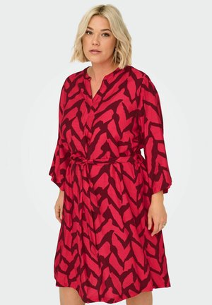 Robe rouge avec un motif abstrait noir, décolleté en V, manches longues et ceinture à la taille. Fabriquée en tissu léger avec une coupe décontractée.