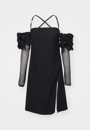 Abito nero con maniche a sbuffo scollate sulle spalle e maniche lunghe trasparenti a pois. Presenta uno spacco laterale e bretelle incrociate sul retro.