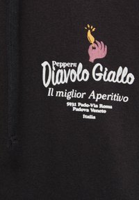 Dłoń trzymająca żółtą papryczkę chili z iskrzącymi się efektami powyżej, tekst "Peppers Diavolo Giallo Il miglior Aperitivo" oraz włoski adres na czarnej tkaninie.