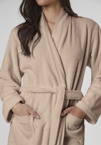 Beige fleece bathrobe featuring a shawl collar, tied waist, and side pockets with textured fabric for warmth and comfort.