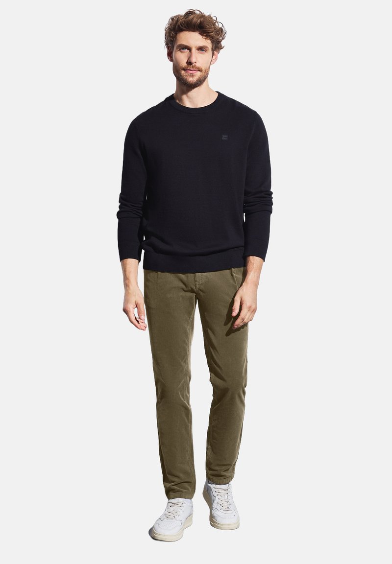 Czarny sweter dzianinowy, khaki chinosy, białe trampki. Prosty, dopasowany krój z prążkowanymi mankietami i pasem. Gładka faktura, swobodny styl.