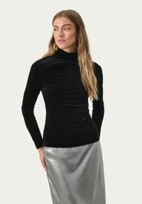 Schwarzer Samt-Turtleneck mit langen Ärmeln, taillierte Passform, glatte Textur, kombiniert mit einem glänzenden silbernen Rock für einen Kontrast.