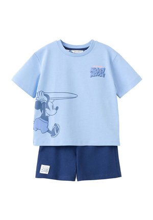 Svetlomodré tričko s krátkym rukávom s grafikou Mickey Mouse držiaceho surfové prkno, v kombinácii s tmavomodrými šortkami s malou nálepkou Mickey Mouse.