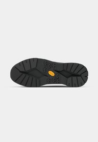 Black shoe sole with a rugged tread pattern, featuring geometric shapes for grip and durability. White background emphasizes the design.