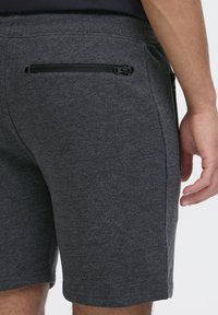 Graue Jersey-Shorts mit elastischem Bund, ausgestattet mit einer Reißverschlusstasche auf der Rückseite und glatter Textur. Kurze Länge und figurnaher Schnitt.