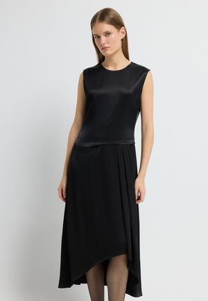Sort ærmeløs kjole i en glat, satinlignende finish; har en asymmetrisk nederdel og bløde plisseringer i taljen.