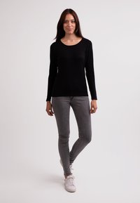 Svart långärmad topp matchad med grå slim fit jeans och vita sneakers. Toppen har en rund halsringning och en åtsittande design.