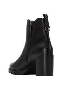Botas de cuero negro hasta el tobillo con cremallera lateral, punta redonda y un tacón grueso y texturizado. Presenta una lengüeta en la parte posterior y suela resistente.