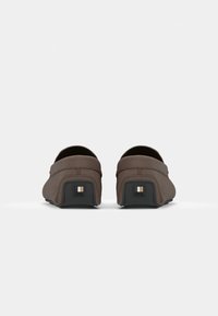 Brune læder slip-on sko med rund tå og flad hæl. Tekstureret overdel med lav profil og kontrasterende sort gummisål.