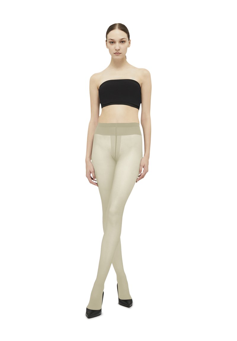 Beige strømpebukser med en glat tekstur og en høj talje, parret med en sort bandeau-top. Modellen står i sorte højhælede sko.