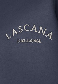 Felpa blu navy con tessuto testurizzato. Presenta la scritta ricamata bianca "LASCANA" e "LUXE.LOUNGE" posizionate sulla parte anteriore.