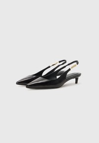 Des escarpins à bride arriére noirs avec un bout pointu, en cuir lisse. Ils présentent un talon fin et un détail en métal doré sur la sangle.